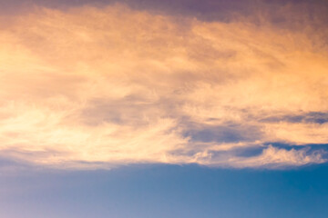 Wall Mural - orange cloud on blue sky at sunset. beautiful nature background at dusk for meteorology. cloudscape in yellow light. abstract scene of summer weather