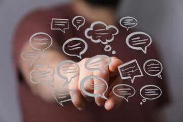 Wall Mural - Hand reaching out towards a group of digitally-placed speech bubbles, suggesting communication or connection on screen.