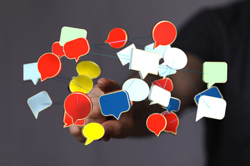 Wall Mural - A person's hand connecting colorful speech bubbles, representing communication, ideas, and social networking. Perfect for articles and designs a