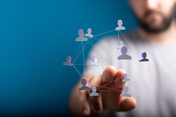 Wall Mural - A hand touching a network of human icons representing communication, connection, teamwork, and global networking on blue background. Concept of