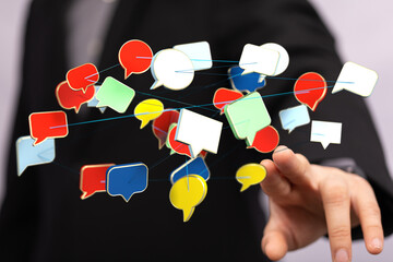 Wall Mural - Close-up of a hand touching floating colorful chat bubbles. Illustrating communication, network, online interactions, and social media.