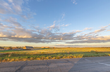 Wall Mural - Field with a barn in the background and a cloudy sky