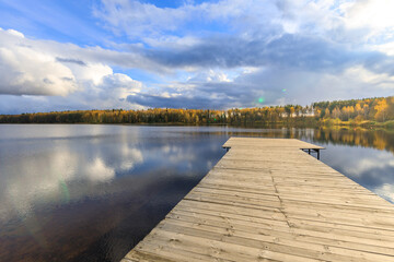 Wall Mural - Dock is on the edge of a lake with a cloudy sky in the background