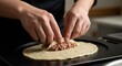 © Desi - Hands shaping a dough with meat filling on a griddle for cooking