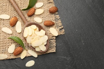 Wall Mural - Fresh almond flakes, whole nuts and green leaves on grey table, flat lay. Space for text