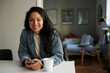 © Johnér - Portrait of smiling woman holding smart phone while sitting at dining table