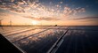 © Omar Studio - Solar Panels Reflecting Sunset with Wind Turbines in Background; Clean Energy Transition