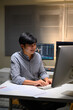 © Prathankarnpap - Young Asian trader analyzing financial charts on computer at night, focused on investment strategy