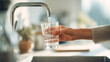 © Taras Vykhopen - Woman fills a glass with water in a bright kitchen setting during the day