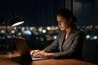 © Maria - Focused freelancer works by lamplight against softly glowing city lights in quiet concentration