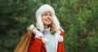© rohappy - Happy smiling young woman with shopping bag in winter against Christmas tree, looking away