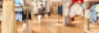 © elenavolf - Blurred interior of modern clothing store with racks and displays on wooden floor.