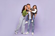 © Home-stock - Portrait of happy family of three parents and their daughter having fun over purple studio background, girl piggybacking dad, full length shot