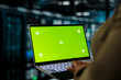 © DC Studio - Close up of programmer using green screen laptop in data center to track metrics of gear used to host websites. Server hub worker upgrading rigs running companies databases using mockup notebook