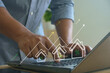 © MUNTHITA - Businessman using laptop with virtual house icons and growth graph, representing real estate investment, mortgage interest rates, property market analytics for financial planning and growth strategy.