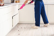 © Pixel-Shot - Female pest control specialist carrying out cockroach disinfection in kitchen