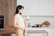© Pixel-Shot - Beautiful pregnant woman with glass of milk in kitchen