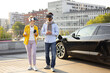 © sofiko14 - A couple wearing VR headsets while their electric vehicle charges in an urban setting.