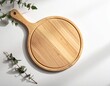 © Reni - Rustic wooden pizza peel with eucalyptus leaves casting shadows on a white surface