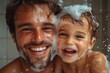 © mobile - Happy father and young son covered in soap suds while taking a bath together, both smiling and enjoying playful bathing moment