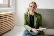 © Westend61 - Woman in green jacket working on tablet in modern loft with copy space