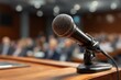 © Dina - Microphone at city hall meeting  or conference, on council podium, blurred audience background. Public talk.
