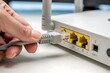© Taslima - Close up of a hand connecting an ethernet cable to a wireless router s lan port for internet setup and connectivity