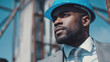 © Katerina Bond - Confident Black male architect in suit and blue hard hat inspecting construction site, symbolizing leadership, engineering and professional development in the building industry.