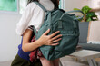 © itchaznong - Affectionate Moment. A mother hugging her daughter while holding a backpack.