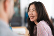 © Studio Marmellata - A woman laughs while talking to someone across a table, sharing a moment of connection and joy in a casual setting.