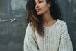 © nsit0108 - Fashion model posing near grey wall, wearing white woolen sweater, looking away from camera