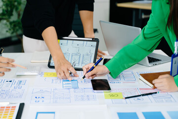 UX developer and ui designer brainstorming about mobile app interface wireframe design with customer breif and color code at modern office.