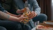 © Yuliia - Close up four unrecognizable friends clinking bottles at home part drinking beer alcohol addiction dependency multiracial people with drinks communicating together on sofa diverse women men with pizza