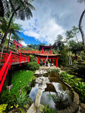 Bright red bridges and tranquil garden pavilion in Madeira Portugal with lush tropical scenery