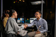 © Wasana - Business partners shaking hands making agreement in office at night