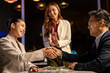 © Wasana - Business colleagues shaking hands making agreement at night office