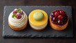 Three Delightful Mini Cakes on Slate Platter with Raspberries, Mint, and Glossy Berry Topping Perfect for Dessert Lovers and Food Photography Sessions