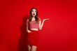 © deagreez - Fashionable young woman in casual outfit expressing surprise against red copyspace background suitable for advertising