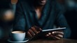 © Thares2020 - A person using a tablet device while sitting at a table with a cup of coffee