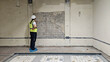 © Egor Lint - Female engineer in safety vest and helmet inspecting damaged concrete wall with exposed reinforcement