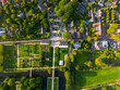 © zlatoust198323 - Aerial view of townv residential zone with trees, central parking and public buildings, formal garden with geometric paths, canal and bridge, blending urban planning with green space symmetry.