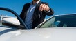 © Space Priest - Man in suit offering car keys next to white vehicle on sunny day