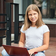 © elenavolf - Caucasian preteen girl enjoying outdoor study with laptop on a sunny day.