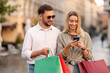 © New Africa - Happy couple with different shopping bags and phone outdoors