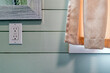 © davidrh - A GFCI electrical outlet in a bathroom next to a curtained window