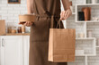 © Pixel-Shot - Female barista with paper bag and container in cafe