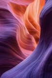 Smoothly carved narrow canyon walls with flowing shapes in vibrant purple and warm orange hues showcasing natural geological formations and textures