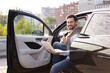 © sofiko14 - A smiling man gives a thumbs up while sitting in a car with a laptop, suggesting success or approval.