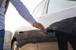 © sofiko14 - A man's hand reaching for the door handle of a sleek, black car, ready to open it.