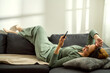 © Cavan - Woman using mobile phone while laying down on  a couch at home